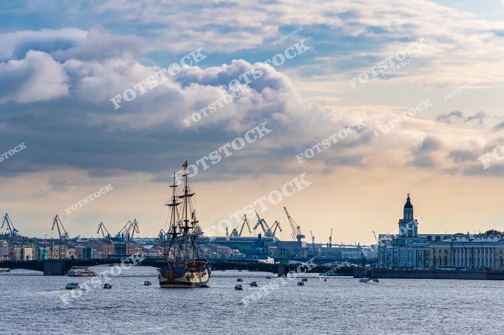 Фотография панорамного вида центра Санкт-Петербург, Россия, сделанная в пасмурный день. На изображении запечатлён парусный корабль, идущий по реке Нева, на фоне Дворцовый мост. Этот фотоснимок передаёт атмосферу северного города, его спокойный ритм и выразительную архитектуру исторического центра. Фото подчёркивает красоту рек Санкт-Петербурга и символично отражает образ российских городов. Иллюстрация может использоваться как картинка или слайд, посвящённые городским пейзажам и водным маршрутам Петербурга.